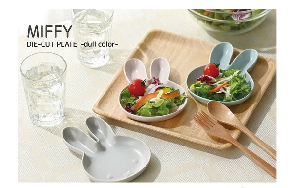 Miffy-shaped ceramic plates with salad on a wooden tray with glasses and cutlery.