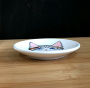 White ceramic dish with a cat illustration on a wooden surface