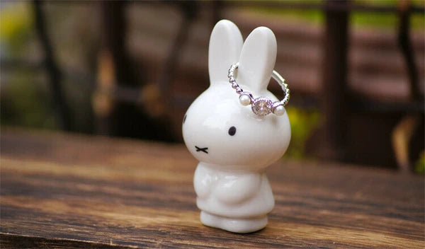 White rabbit figurine with a ring on a wooden surface