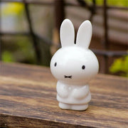 White rabbit figurine on a wooden surface with a blurred natural background